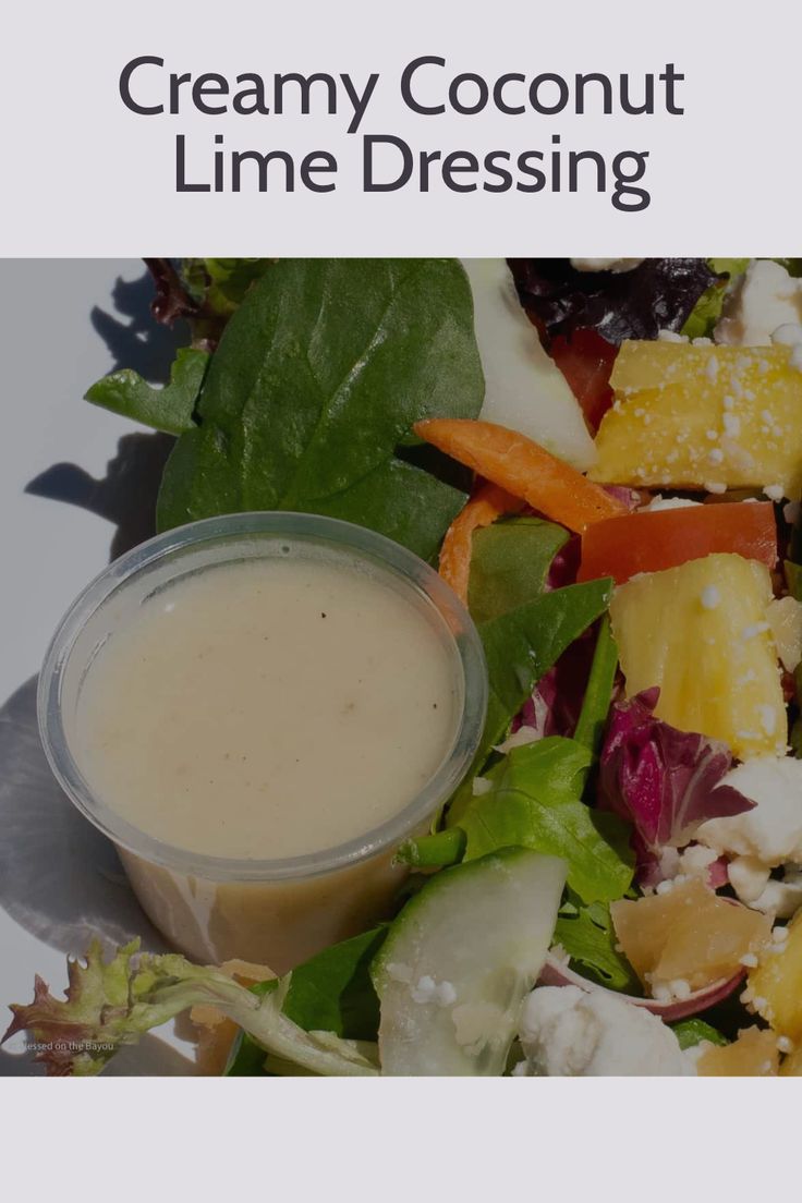 a white plate topped with salad and dressing next to a cup of creamy coconut lime dressing