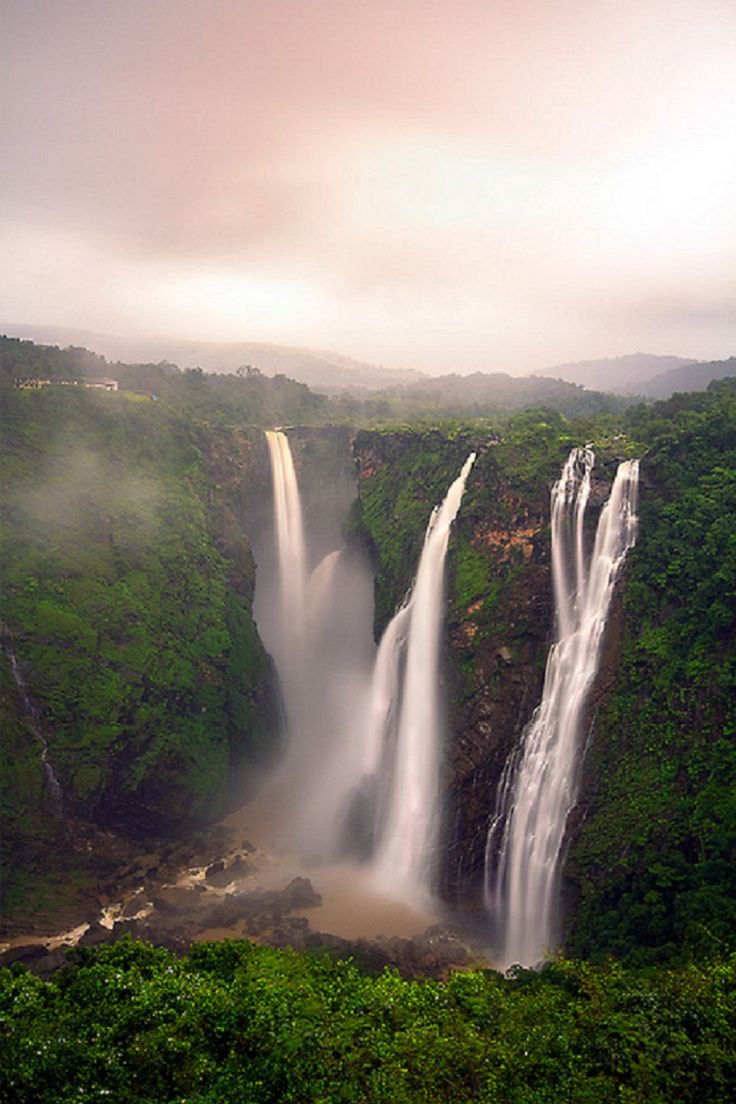 a large waterfall surrounded by lush green trees