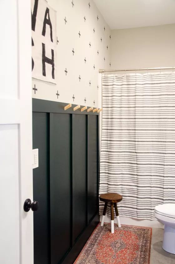 a white toilet sitting next to a black door in a bathroom on top of a rug