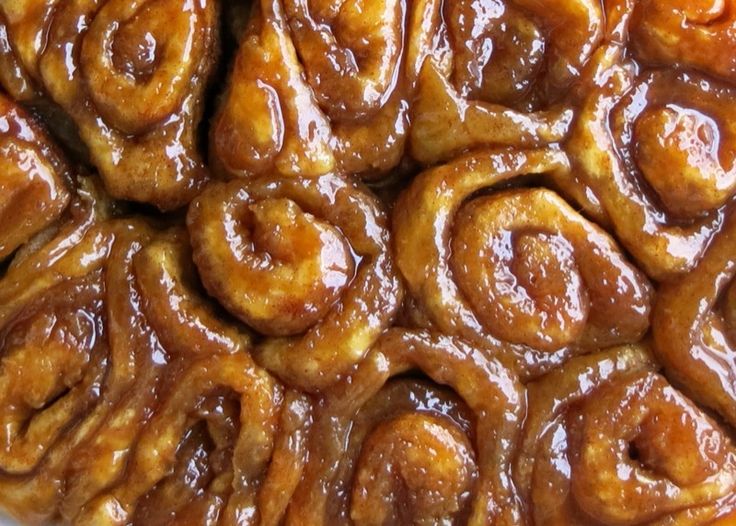 a close up view of some cinnamon rolls on a white plate with caramel sauce