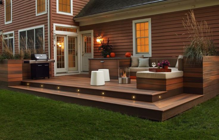 a deck with lights on it next to a house and an outdoor living area in the background