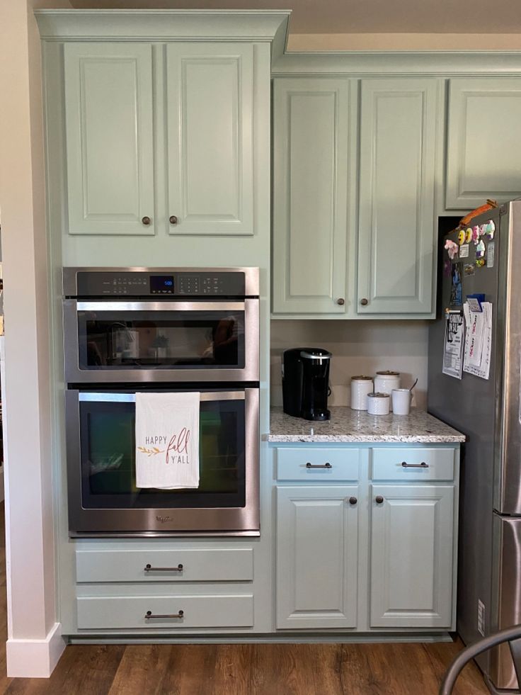 a kitchen with light green cabinets and stainless steel appliances