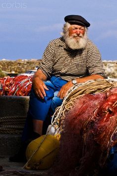 an old man sitting on the back of a truck next to some bags and other items