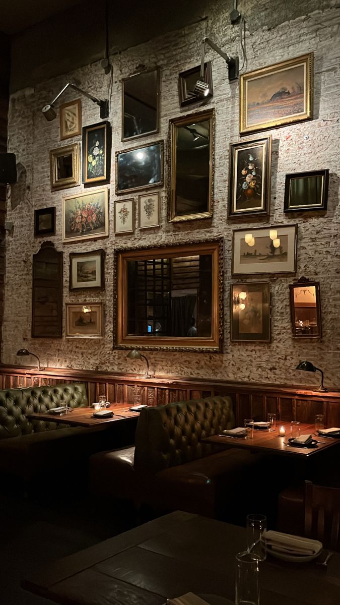 a dimly lit restaurant with many framed pictures on the wall and couches in front of it