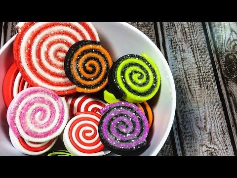 a white bowl filled with assorted colored lollipops on top of a wooden table