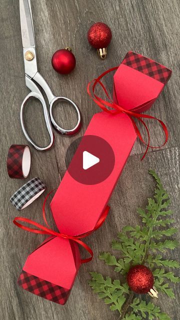 a pair of scissors sitting on top of a wooden table next to red wrapping paper