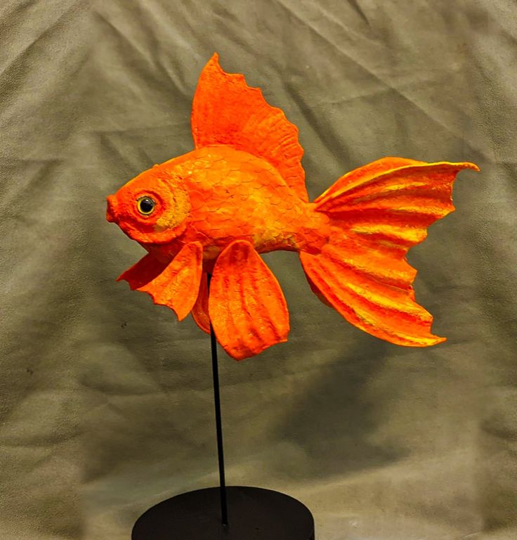 an orange plastic fish on a black stand