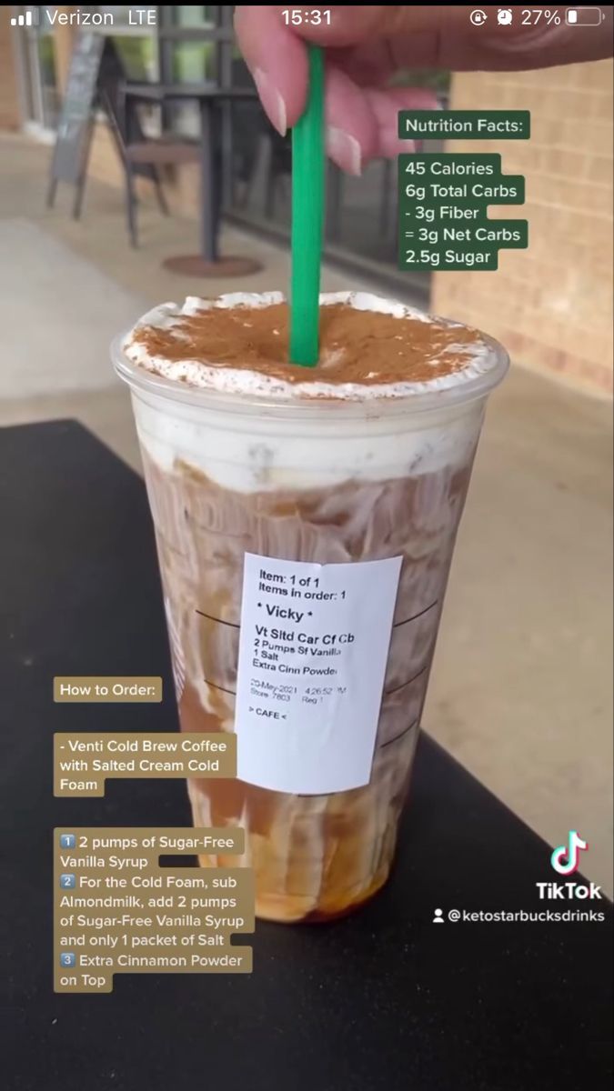 a person is holding a green straw in a cup with ice cream and caramel