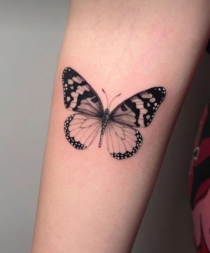 a black and white butterfly tattoo on the arm