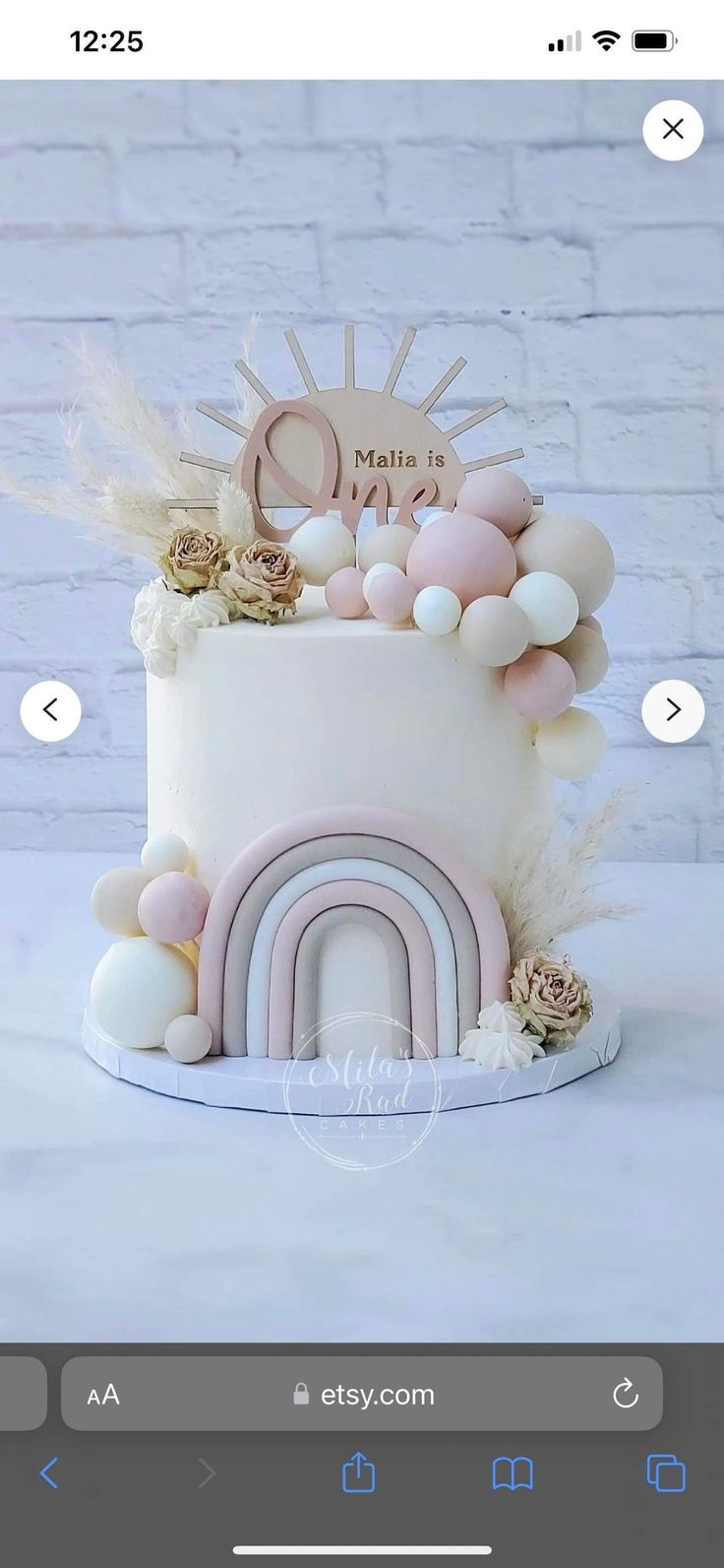 a white cake with pink and gold decorations on it's top, sitting on a table