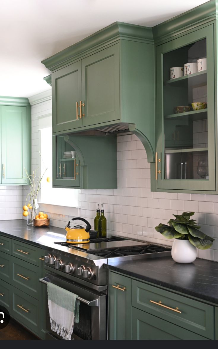 a kitchen with green cabinets and black counter tops