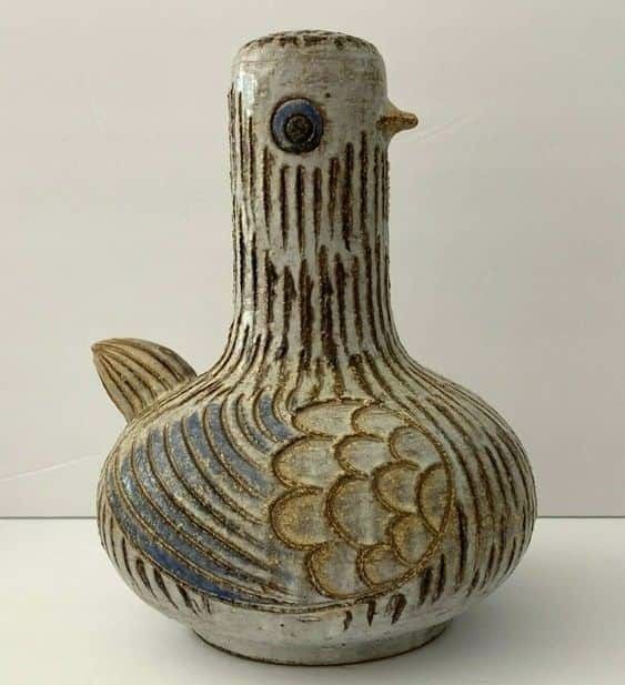 an old vase is sitting on a white tableclothed surface with lines and fish designs