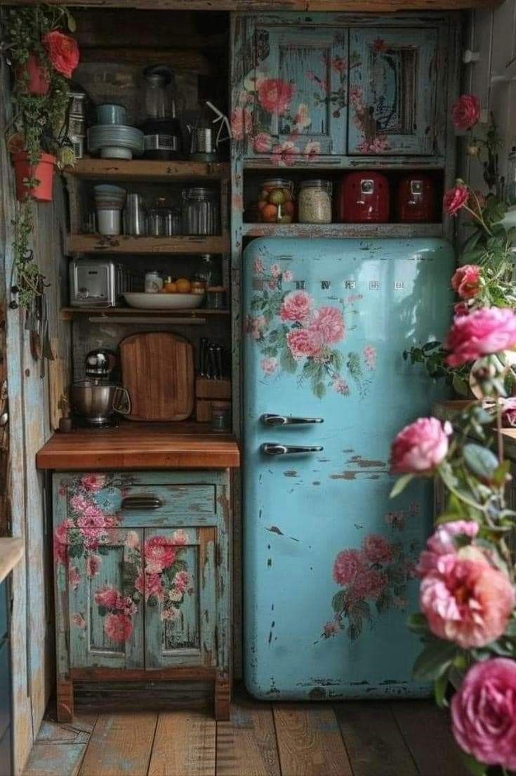 an old blue refrigerator in a kitchen with pink flowers on the wall and wooden flooring