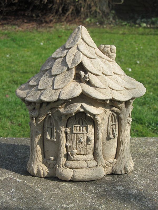 a small clay house sitting on top of a cement slab in front of some grass