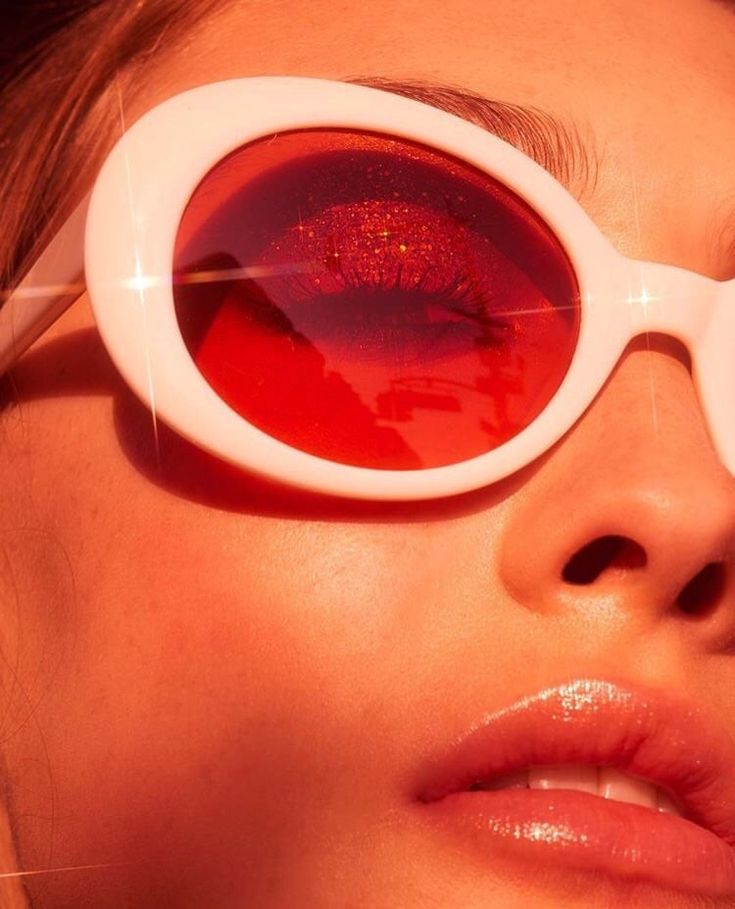 a woman wearing large white sunglasses with red liquid on her face and eyeliners