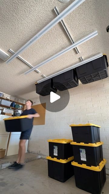 a man moving boxes in a storage room with the ceiling exposed and overhead lighting on