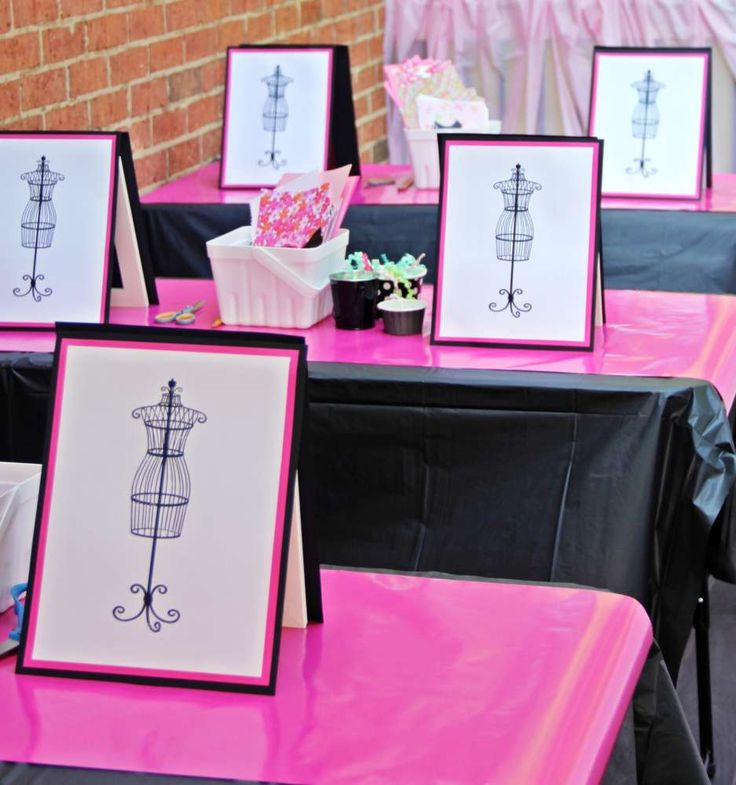 pink and black tables topped with pictures and vases on top of each table in front of a brick wall