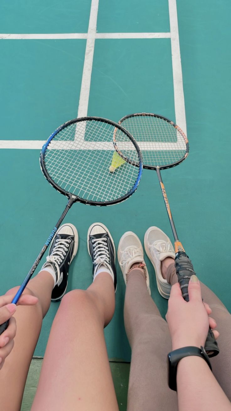 two people sitting on a tennis court holding rackets