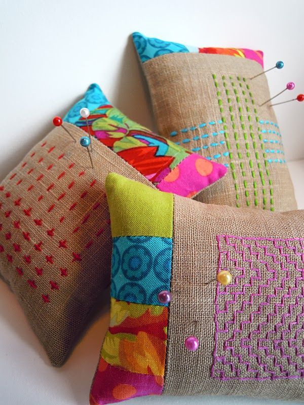 three decorative pillows on a white surface with pins in the middle and buttons at the back