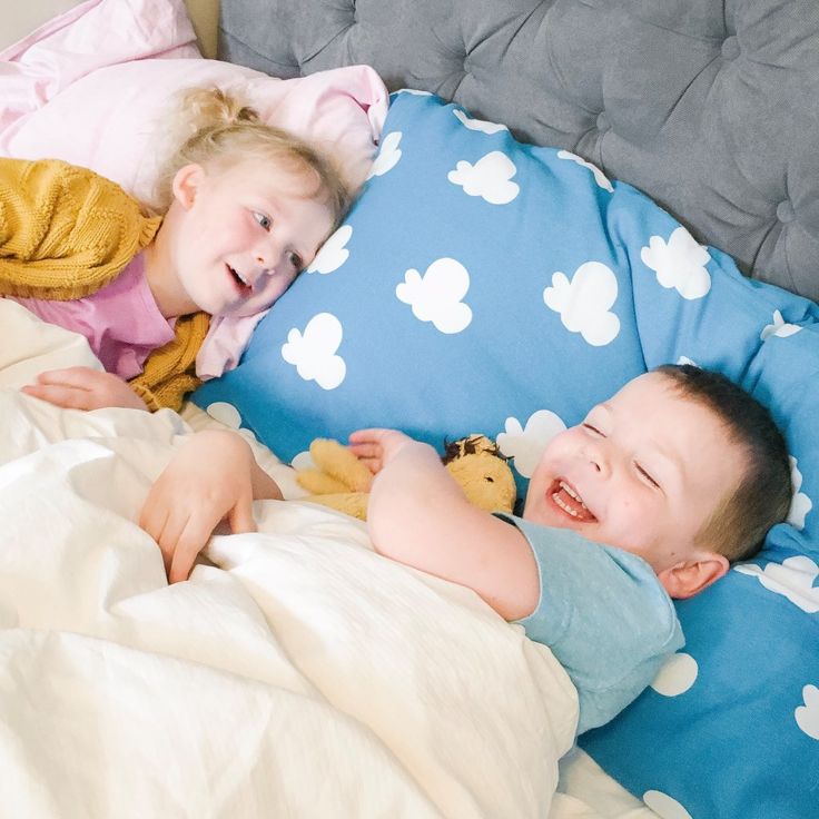 two small children laying in bed next to each other