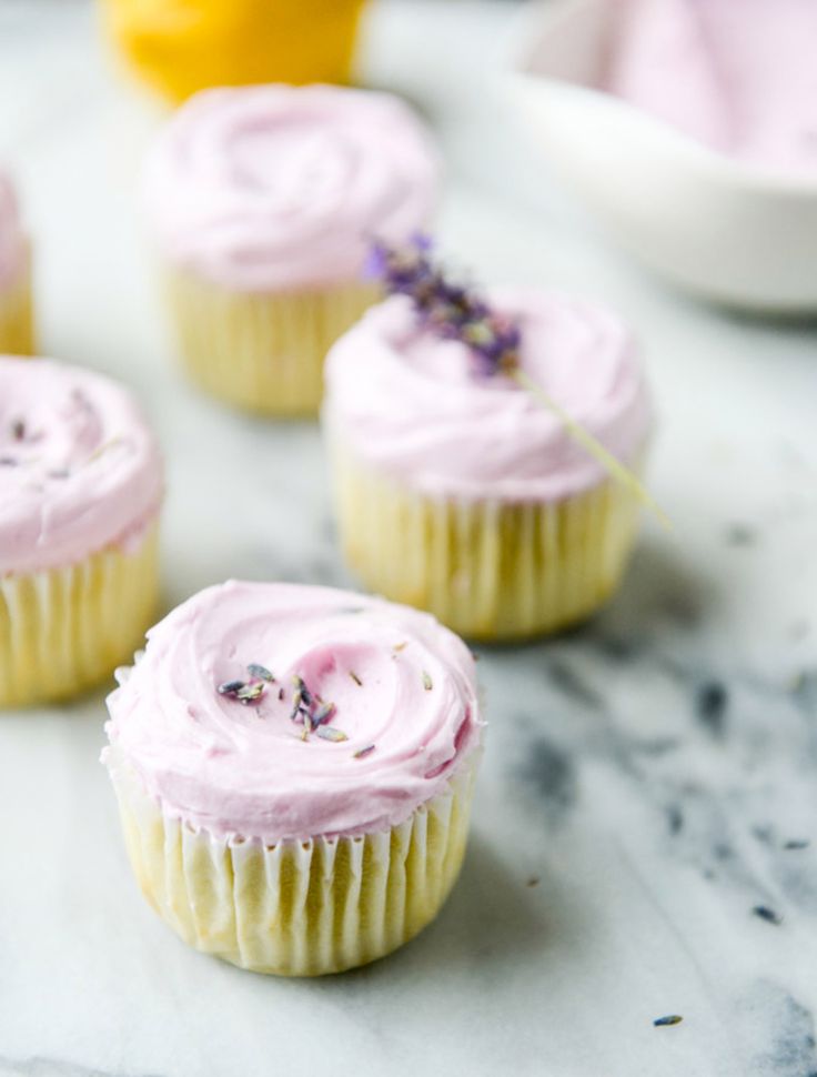 cupcakes with pink frosting and lavender sprinkles on a marble surface