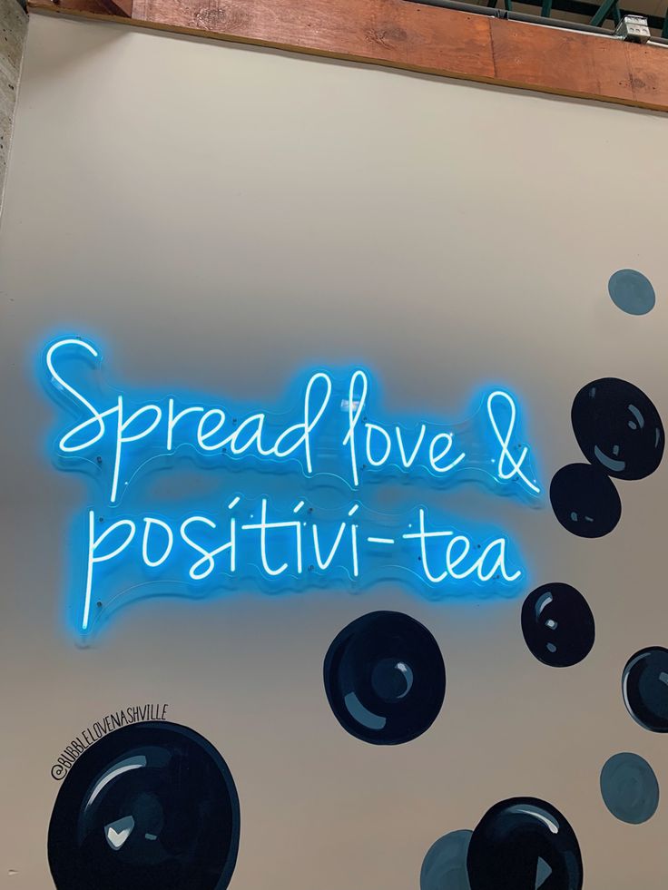 a neon sign that says spread love and positiv - tea on the wall