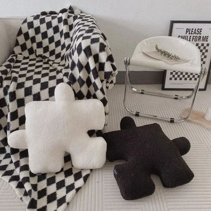 two black and white teddy bears sitting next to each other on a rug in front of a chair