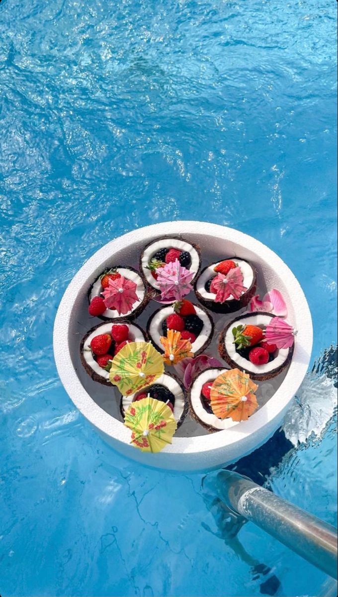 an arrangement of sushi in a bowl on the edge of a swimming pool