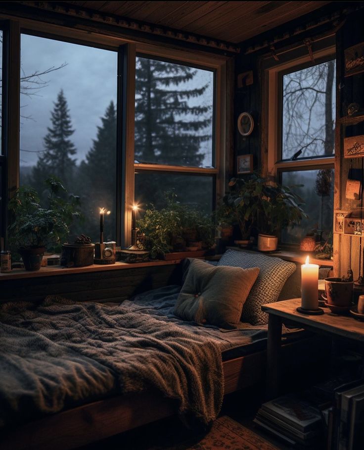 a bed sitting in a bedroom next to a window with candles on top of it