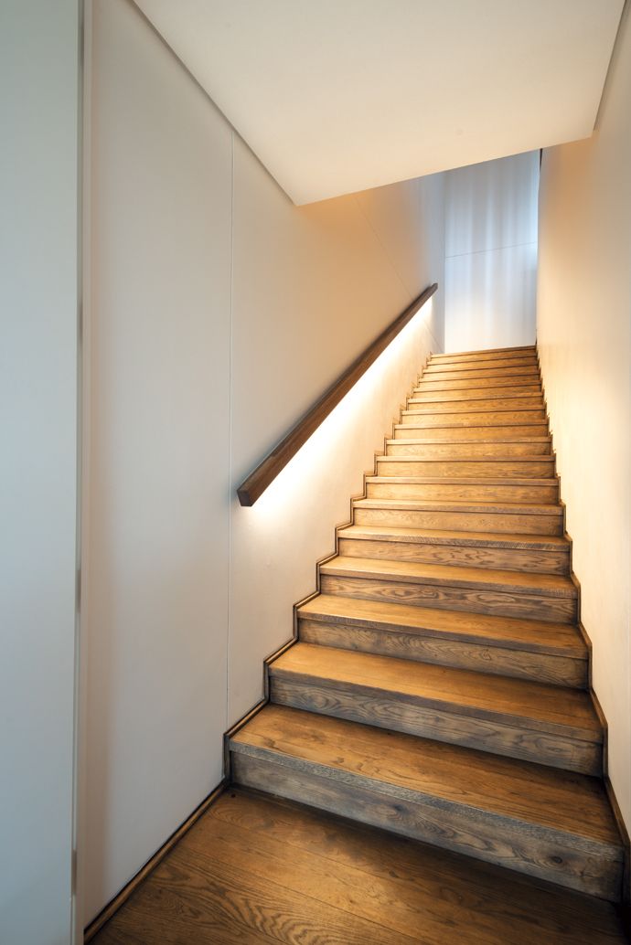 an empty staircase with wooden steps leading up to the second floor and light coming from above