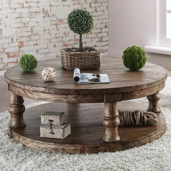 a round wooden table sitting on top of a white rug in front of a brick wall