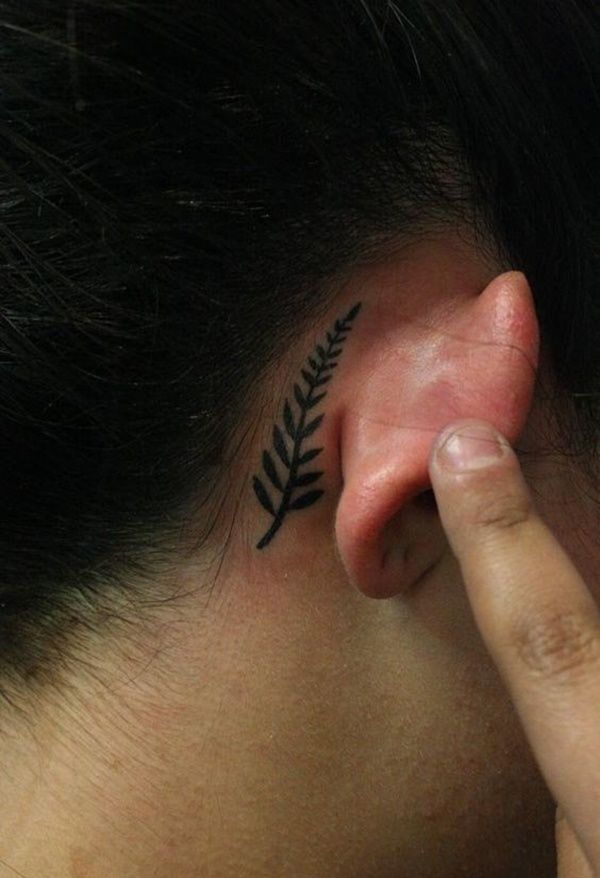 a close up of a person's ear with a fern tattoo on their left side