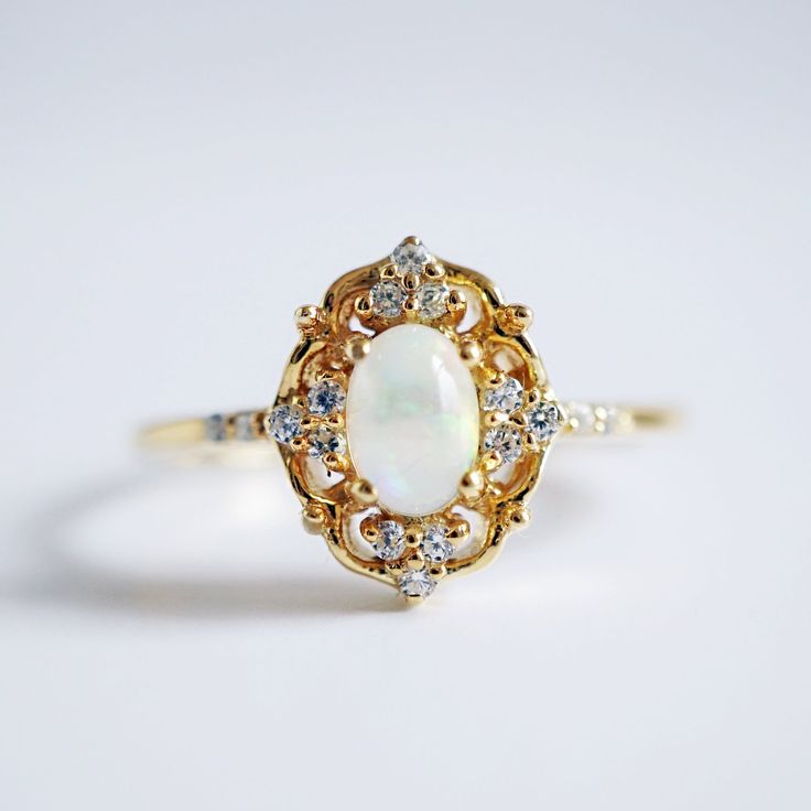 "We all shine on...like the moon and the stars and the sun..." Stare into the Cosmic Opal ring and you might just see another universe. A beautiful opal set in solid sterling silver with a layer of thick 14k yellow gold, orbited by sparkling white CZs symbolizing tiny stars. Available in yellow gold, rose gold and silver, or 14K solid gold. 925 solid sterling silver in 14K solid gold Natural 6x4mm Ethiopian opal center stone Round CZs (what's this?) **This item is specially made for you. Please Celestial 14k Gold Opal Wedding Ring, White Opal Celestial Ring, Celestial White Opal Ring, Celestial 14k Gold Opal Gemstone Ring, Celestial 14k Gold Opal Ring, 14k Gold Celestial Opal Ring, Celestial Opal Ring With Halo For Anniversary, Celestial Halo Opal Ring For Anniversary, Celestial Style Opal Ring With Halo For Anniversary