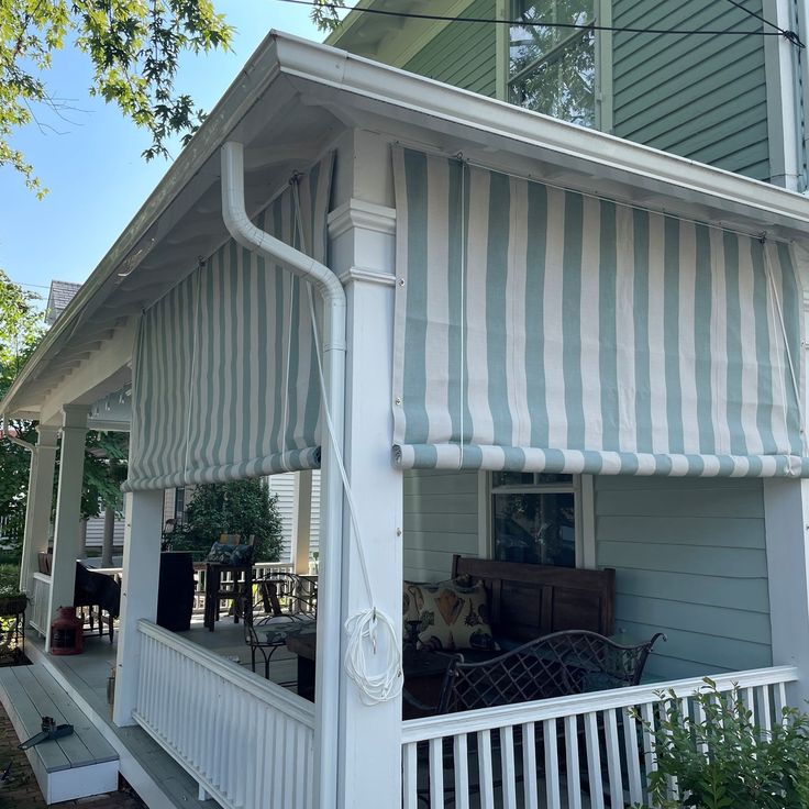 a white and blue striped awning on the front of a house with porch furniture