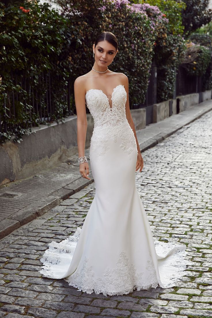 a woman in a wedding dress standing on a cobblestone street