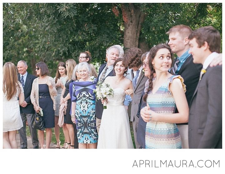 a group of people standing next to each other in front of a tree and grass field