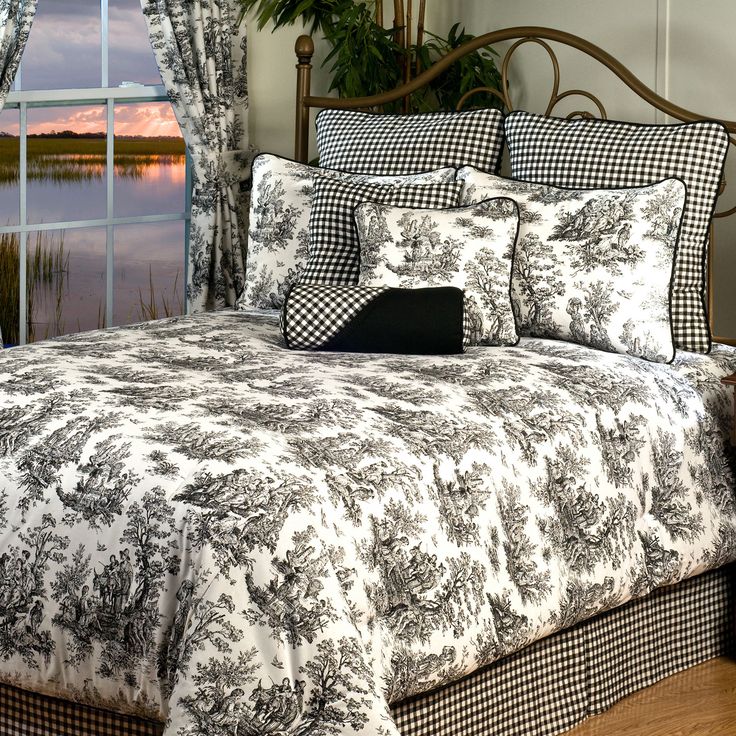 a bed with black and white comforter in front of a window overlooking the water