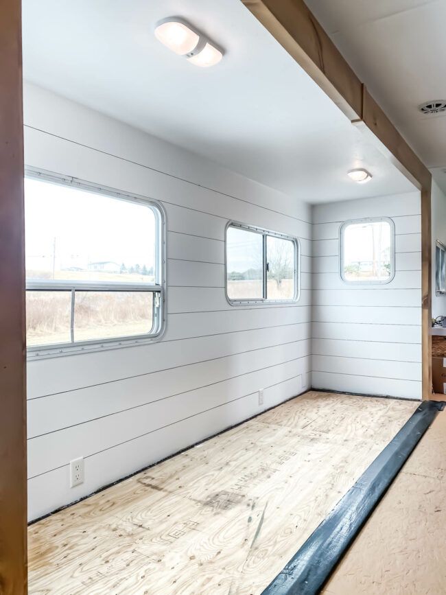 an empty room with wood flooring and windows