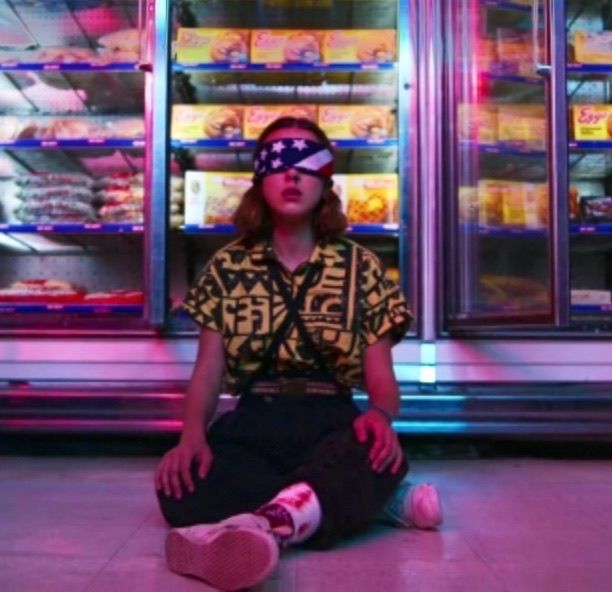 a woman sitting on the floor in front of a vending machine with blindfolded eyes