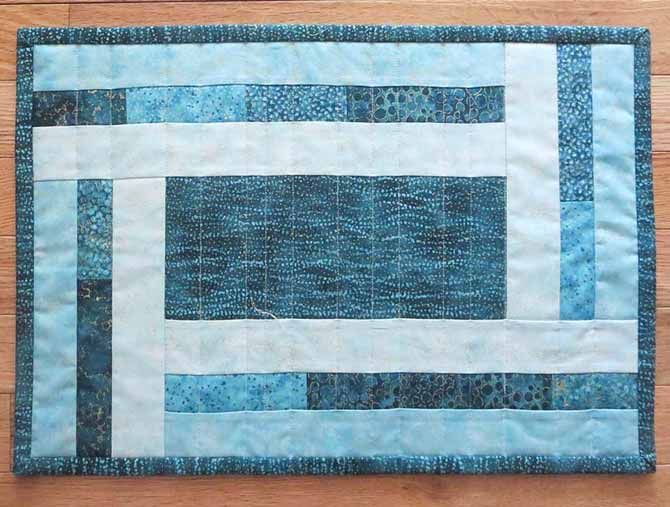 a piece of blue and white quilted material on a wooden floor with wood floors