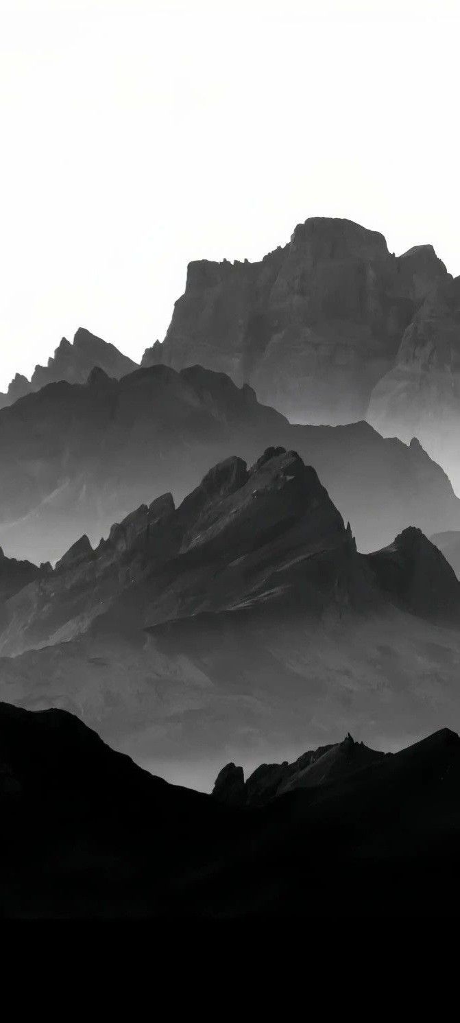 black and white photograph of mountains in the distance with fog coming off from behind them