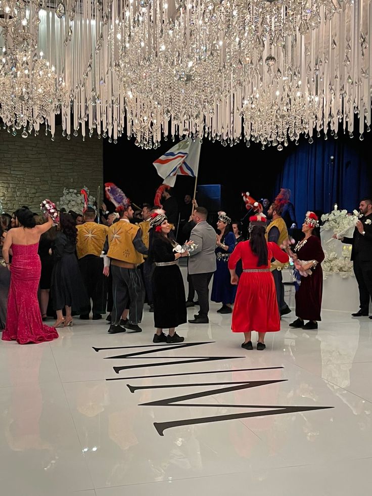 a group of people standing around each other in a room with chandeliers hanging from the ceiling