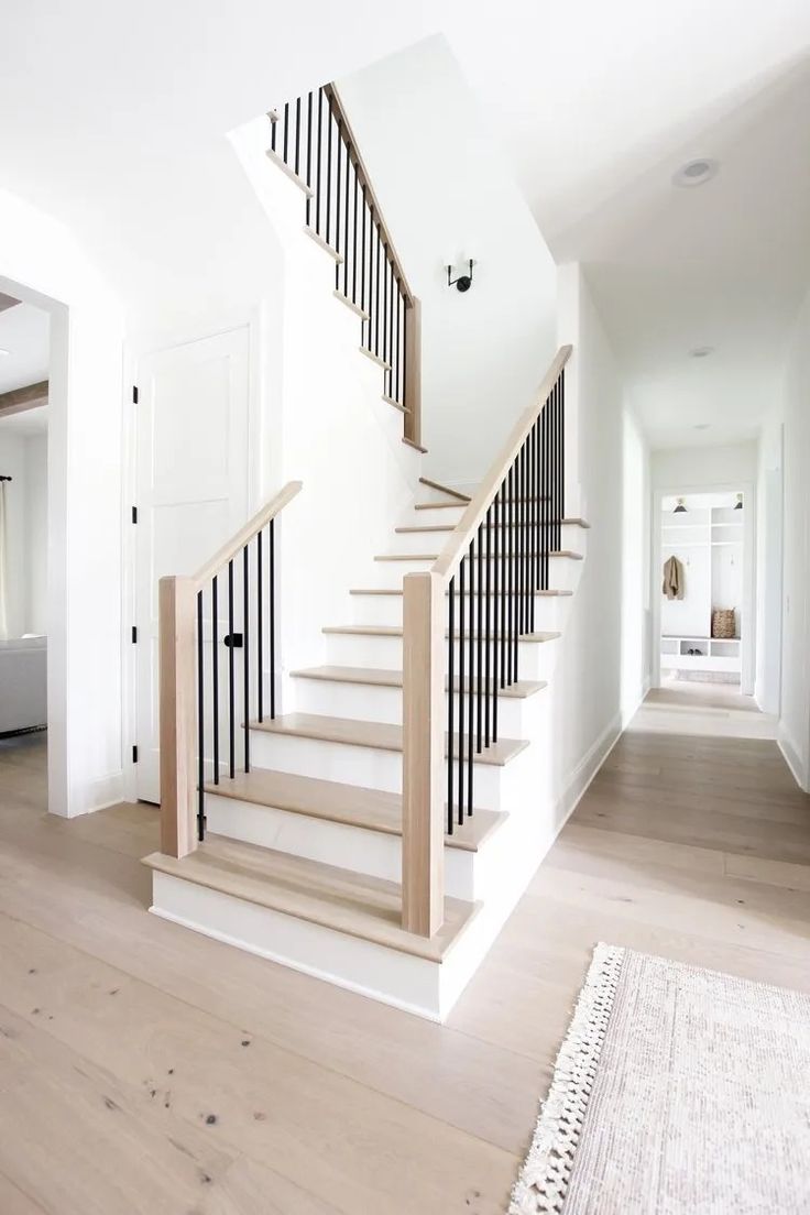 a white staircase with black railing and wooden handrail