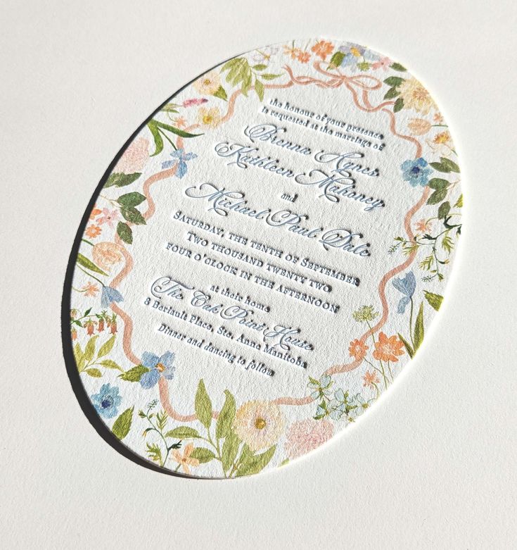 a wedding card with floral designs on the front and back, printed in white paper