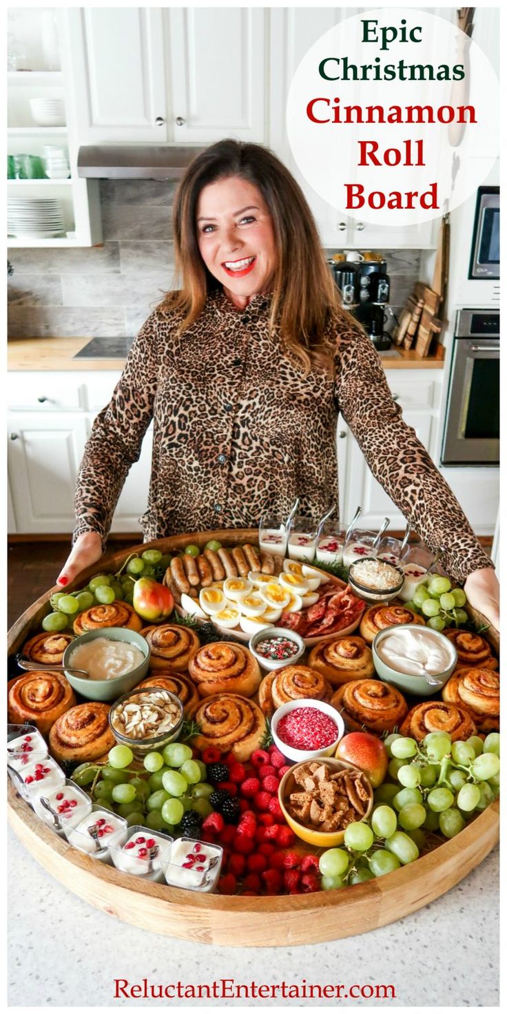 a woman standing in front of a large platter of food with the words epic christmas cinnamon roll board