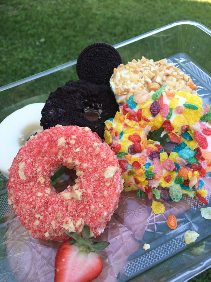 a plastic container filled with lots of different types of donuts and toppings on top of each other