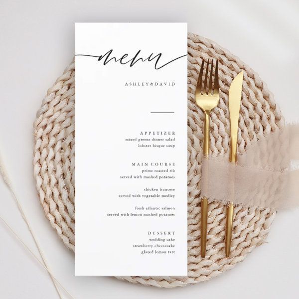 a place setting with a menu and gold utensils on a white table cloth