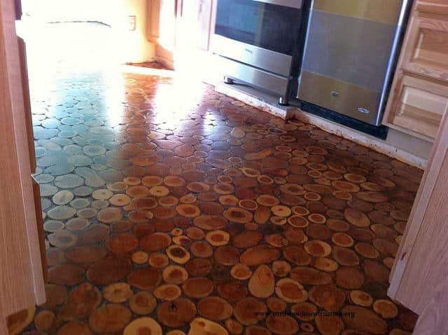 an open door leading into a kitchen with wood slices on the floor and stainless steel appliances