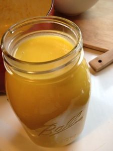 a glass jar filled with liquid sitting on top of a table next to a cutting board