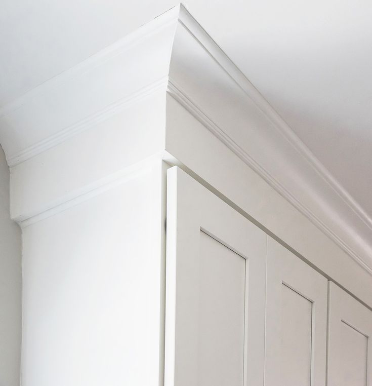 the corner of a kitchen with white cabinets and cupboards on either side of it